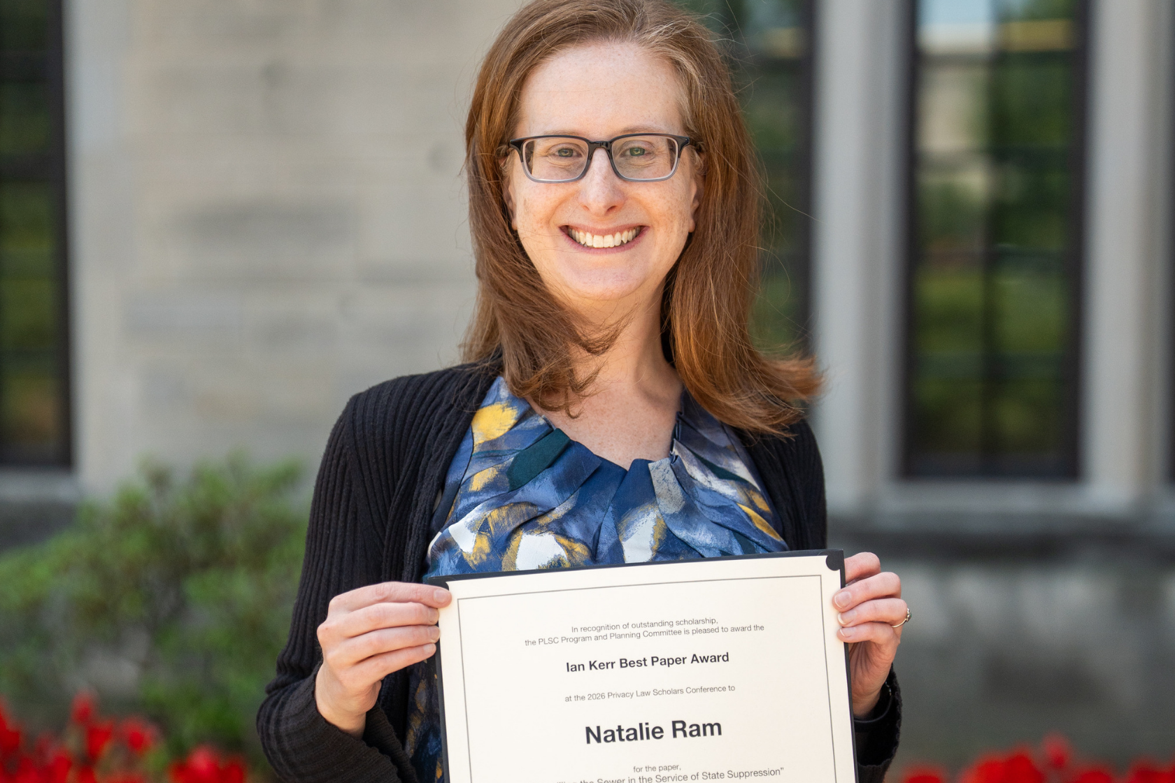 Headshot of person smiling holding a certificate